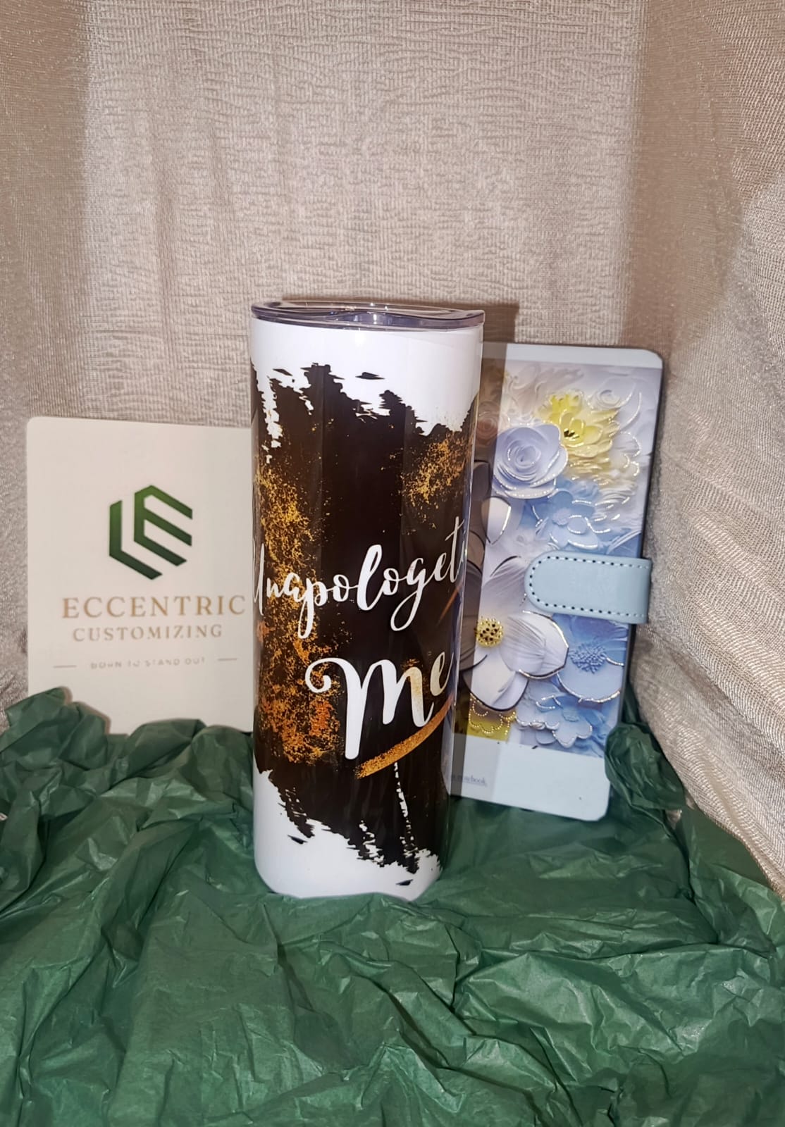 Tumbler with text, card, and notebook on a textured surface